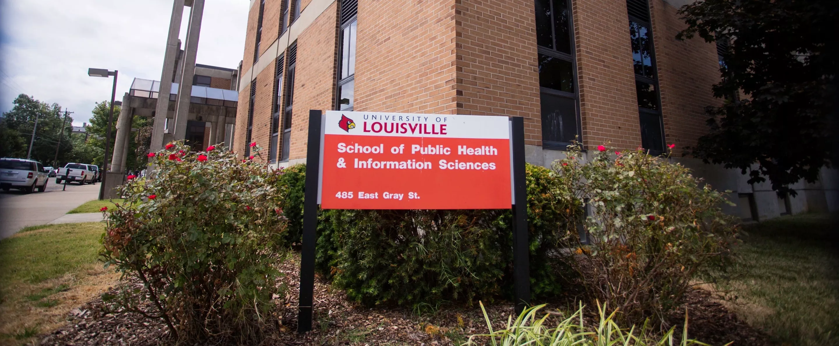 red and white sign in front of building that says University of Louisville School of Public Health and Information Sciences,…