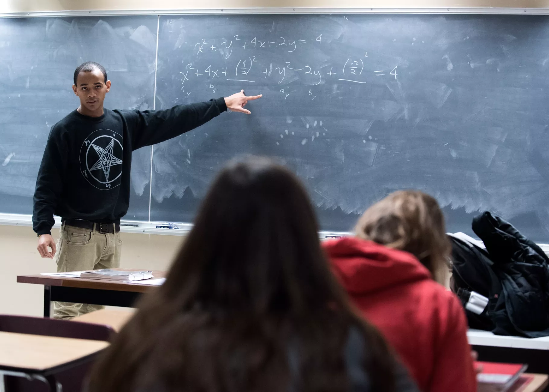 Professor teaches students math problems using the chalk board