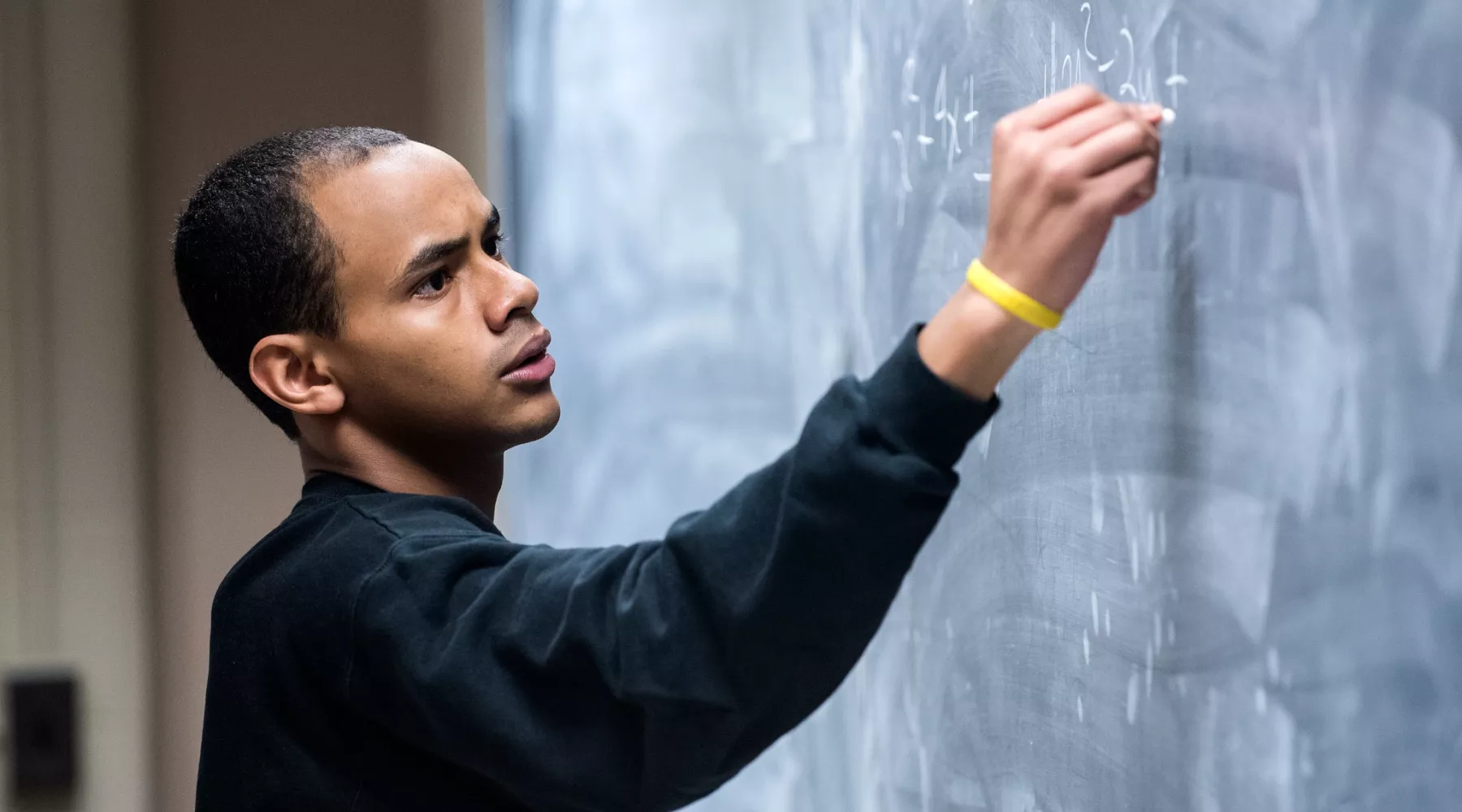 Professor writes out math problems on the chalk board