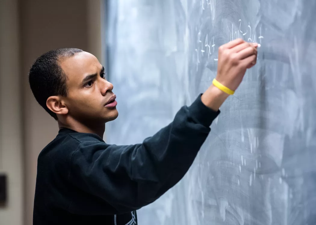 Professor writes out math problems on the chalk board