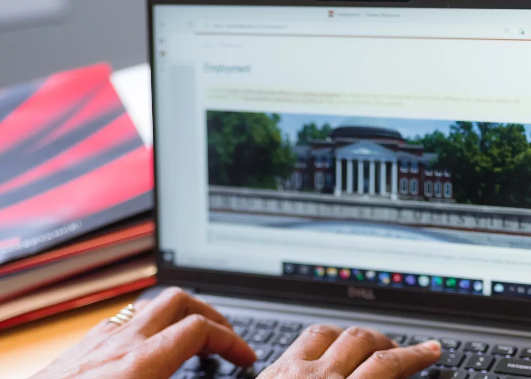 Employee typing on laptop in a UofL office