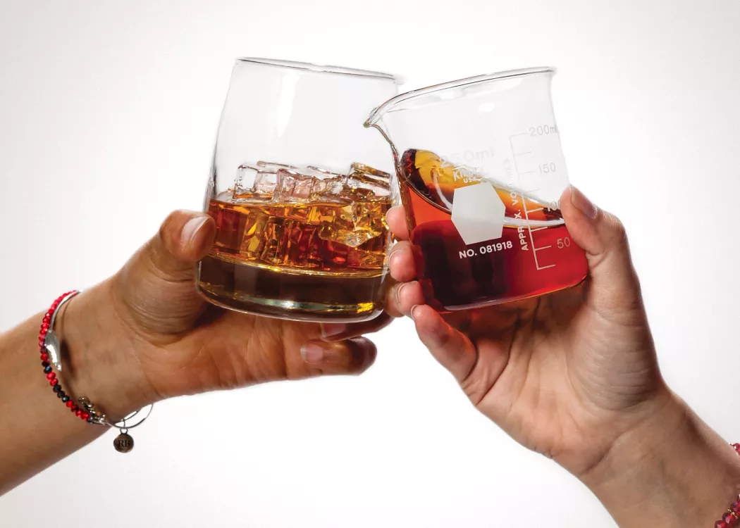 Two women clinking glasses of bourbon
