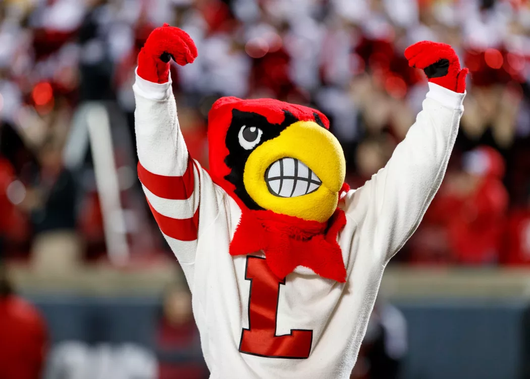 Louie the Cardinal Bird mascot cheering in front of a crowd