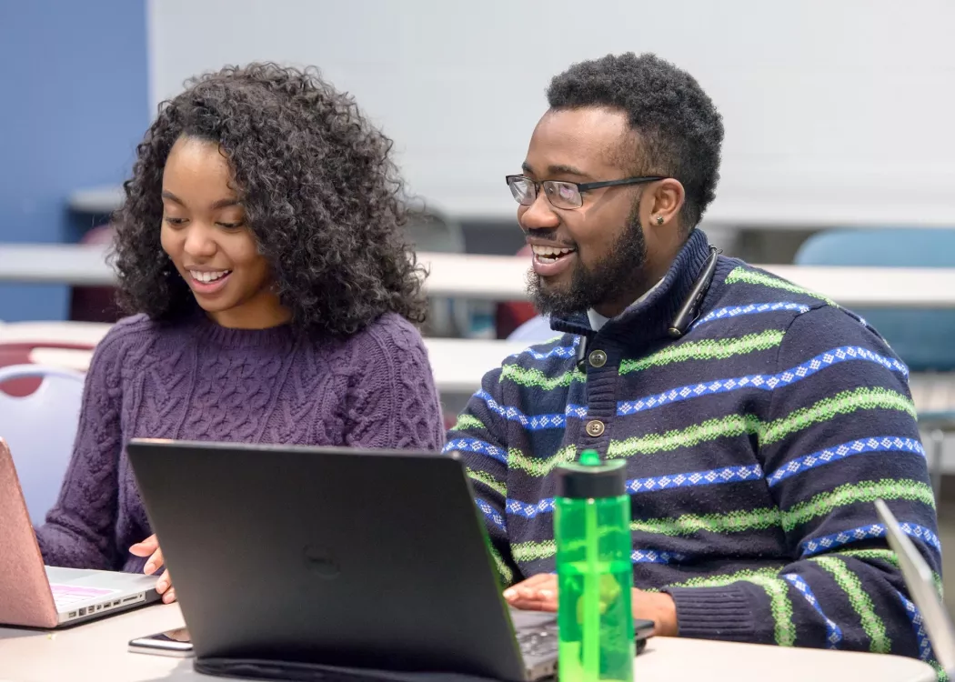 Health Management students in class looking at computers and smiling