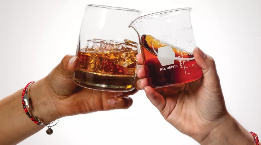 Two women clinking glasses of bourbon